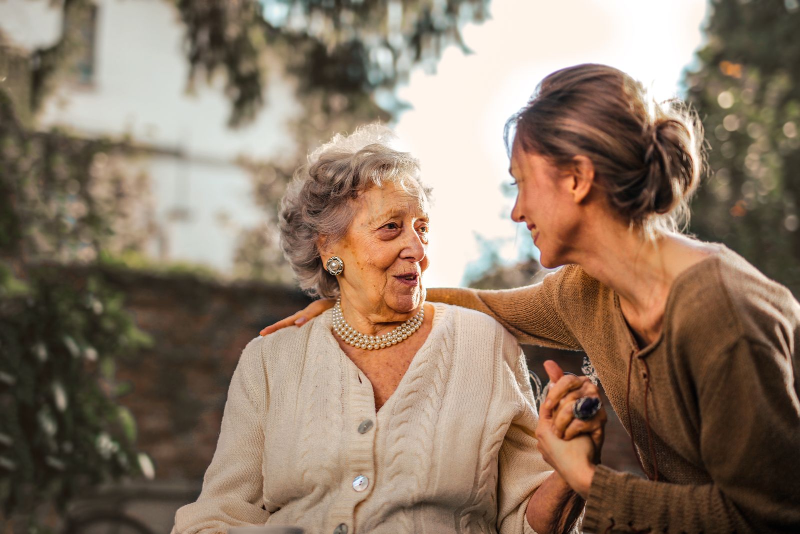 An elderly woman and a younger family member together outdoors, photographed with dignity.